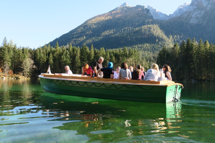 Eine Gruppe von Leuten auf einem kleinen grünen Boot auf einem kleinen See